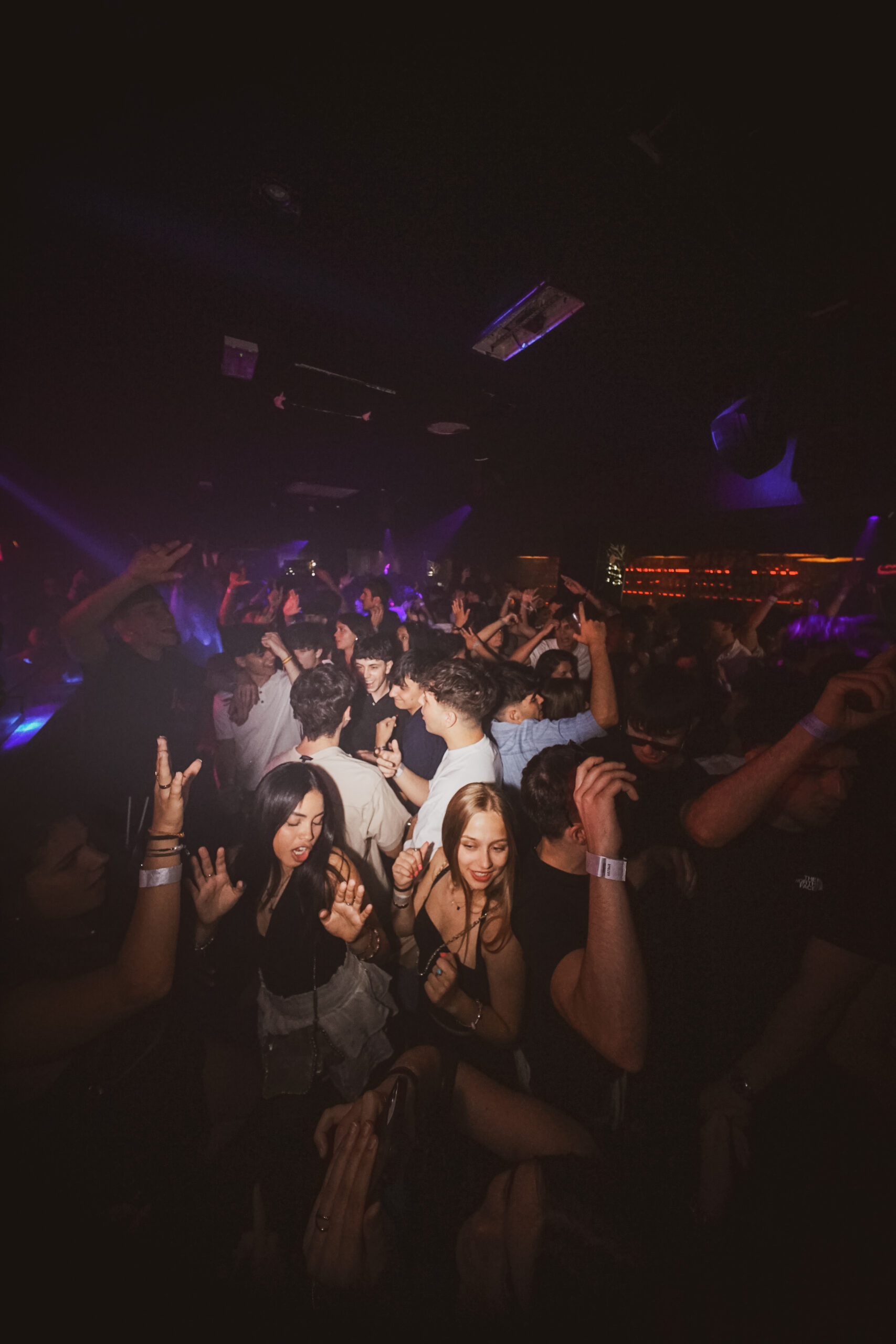 Multitud disfrutando de la fiesta Loca Escandalosa en Shadow Club, Paceville, con luces llamativas y DJ en acción.