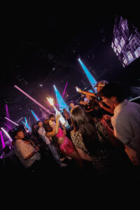 Foto de la fiesta Loca Scandalosa en Malta, con luces de colores y público disfrutando de la música.
