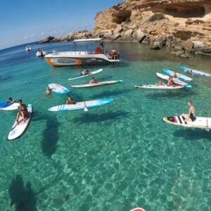 Persona de pie sobre una tabla de paddle surf en una bahía de Malta
