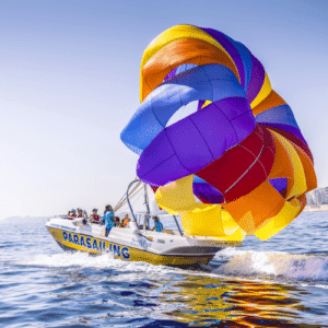 Dos personas practicando parasailing sobre el mar con vistas a la costa de Malta