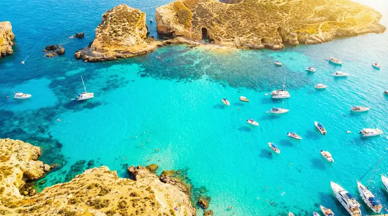 Vista de una playa de Malta con aguas turquesas y costa rocosa.